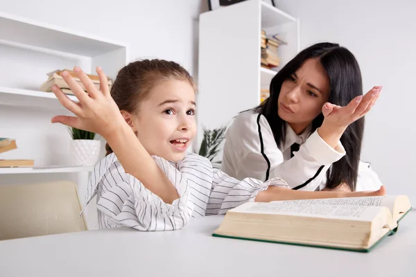 Mamma e figlia leggono il tempo. Imparare insieme seduti a tavola . — Foto Stock