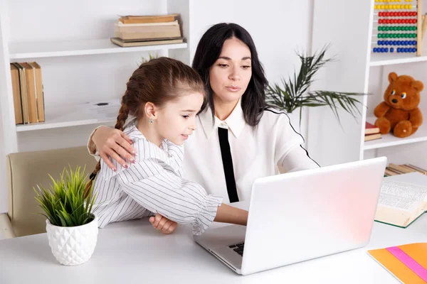 Moeder en dochter zitten met computer samen aan de balie. — Stockfoto