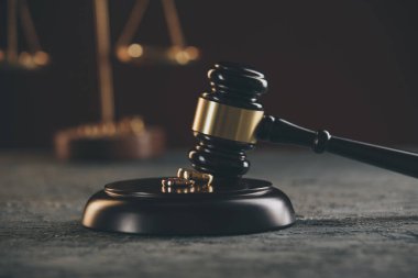 Bir ağaçtan kırık bir kalp figürü üzerinde Alyans, ahşap bir arka plan üzerinde bir yargıç çekiç. Boşanma boşanma işlemleri