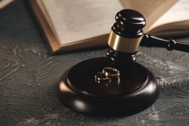 Bir ağaçtan kırık bir kalp figürü üzerinde Alyans, ahşap bir arka plan üzerinde bir yargıç çekiç. Boşanma boşanma işlemleri