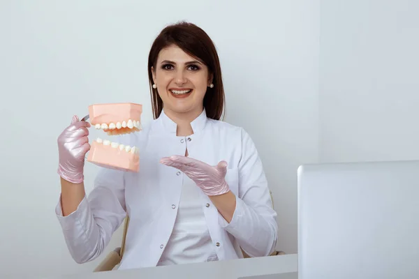 Woman dentist sitting at the table in office with dental staff isolated.