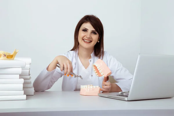 Kobieta dentysta siedzi przy stole w biurze z dentystą na białym tle. — Zdjęcie stockowe