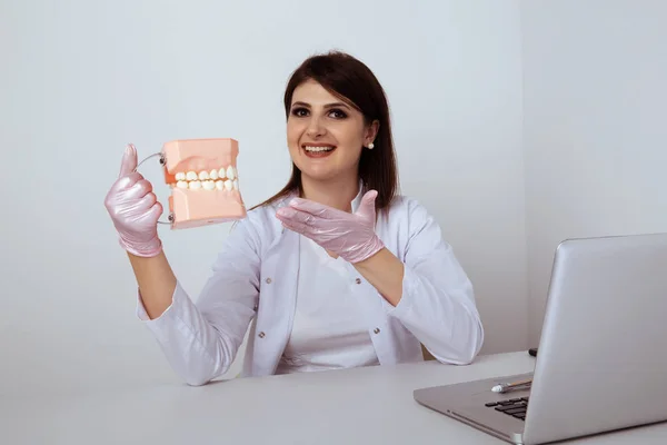 Kobieta dentysta w mundurze siedzi przy biurku i pracuje z dentystą w biurze. — Zdjęcie stockowe