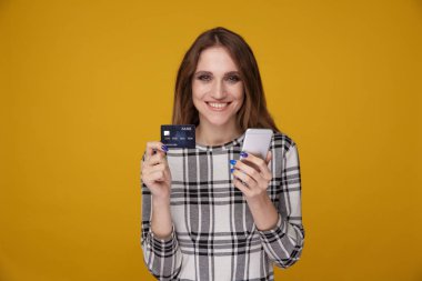 Yakışıklı kadın kredi kartı gösteren ve izole ayakta cep telefonu kullanarak.