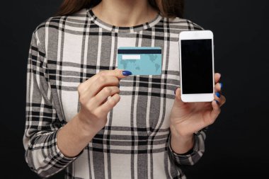 Kadın elinde cep telefonu ve kredi plastik kart Closeup görünümü.