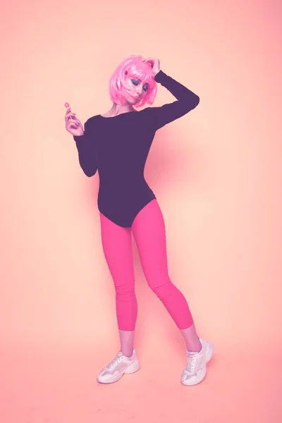 Модель с розовыми волосами, держащими леденец в изолированной студии . — стоковое фото