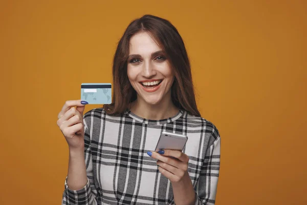 Przystojny kobieta pokazywanie karta kredytowa i przy pomocy telefon stojący izolowany. — Zdjęcie stockowe