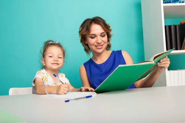 Tutor femminile con bambina che fa i compiti. Concetto prescolare . — Foto Stock