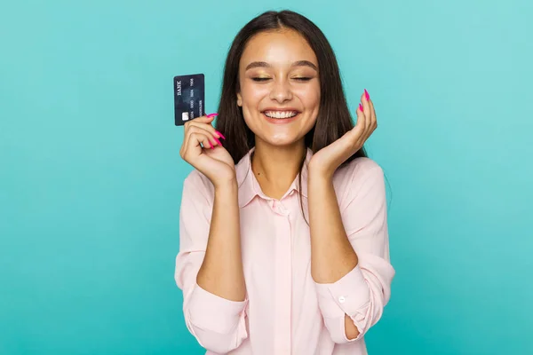 Koncepcja zakupów online. Atrakcyjna kobieta uśmiechnięta i posiadająca kartę kredytową wyizolowana na niebieskim tle. — Zdjęcie stockowe