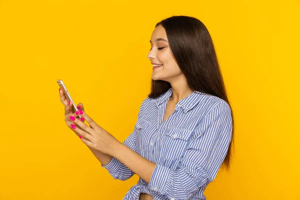 Šťastná krásná žena s telefonem ve žlutém studiu. — Stock fotografie