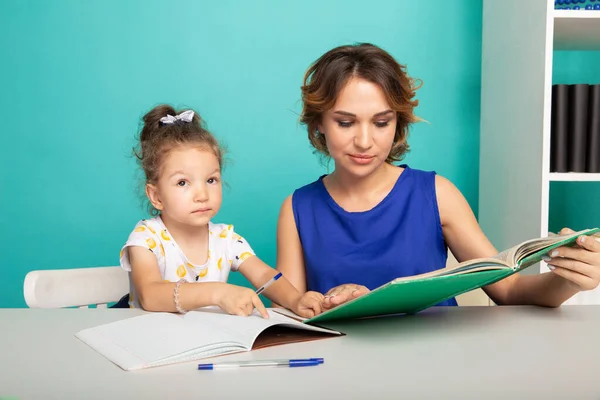 母と娘はテーブルの上で家に座って勉強する. — ストック写真