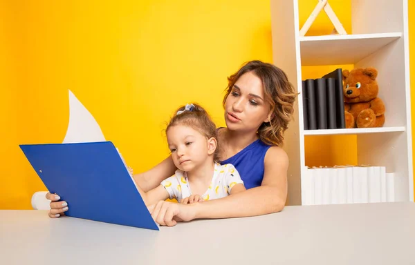 Vrouwelijke tutor met klein meisje doet huiswerk. Preschool concept. — Stockfoto