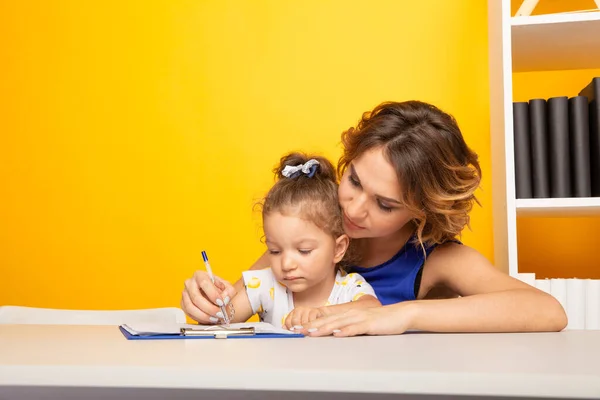 宿題をしている小さな女の子と女性の家庭教師。就学前の概念. — ストック写真