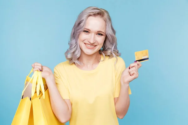 Afbeelding van gelukkig meisje met credit card en big shopping tassen isoleted over de blauwe studio. — Stockfoto