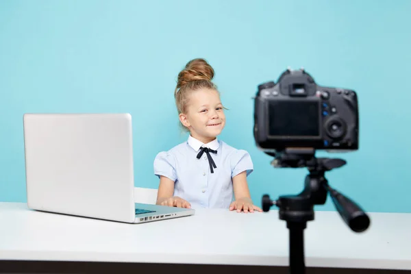 Kid blogger filming video on camera working with the laptop.