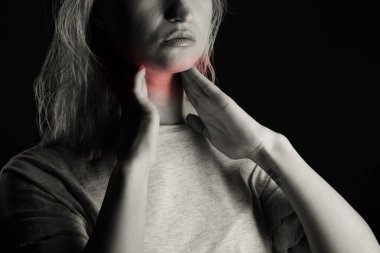 Tiroid bezini tek başına kontrol eden bir kadın. Beyaz tişörtlü bir kadının kırmızı noktalı boynuna dokunuşunu yakından çek. Tiroid bozukluğu guatr, hipertiroid, hipotiroid, tümör ya da kanseri içerir. Sağlık hizmetleri.