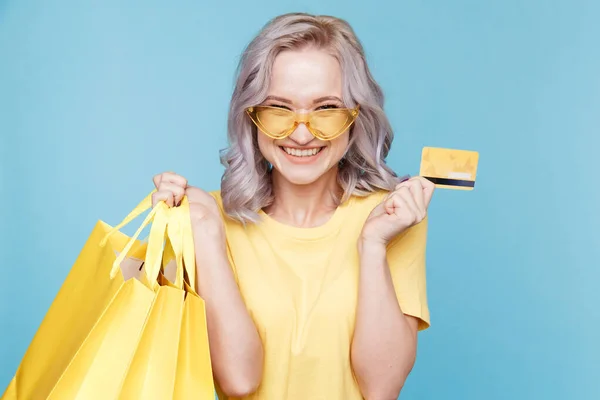 Gelukkig winkelconcept. Schattige vrouw in felgekleurde kleren met tassen en credit card geïsoleerd. — Stockfoto