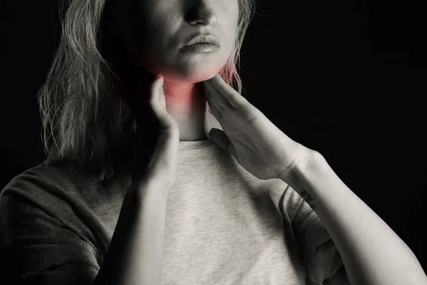 Honan kollar sköldkörteln själv. Närbild av kvinna i vit t-shirt vidrör halsen med röd fläck. Sköldkörtelrubbningar inkluderar struma, hypertyreoidea, hypotyreoidea, tumör eller cancer. Hälsovård. — Stockfoto