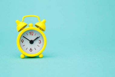 Sarı alarm saati mavi modaya uygun olarak izole edildi. Hayatın dinlenme saatleri. İyi sabahlar. Uyanık kalma kavramı..