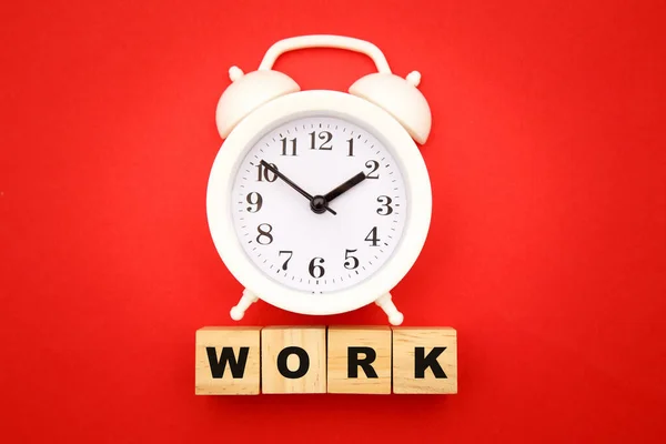 Work Life Konzept. Holzwürfel und Wecker auf rotem Hintergrund — Stockfoto