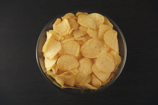 Chips salados crujientes en la placa aislada en el escritorio negro . — Foto de Stock
