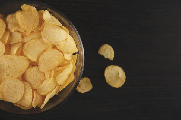 Chips salados crujientes en la placa aislada en el escritorio negro . — Foto de Stock