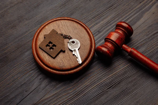 Richtergabel und Schlüsselanhänger in Form zweier geteilter Hausteile auf Holzgrund. Konzept der Immobilienversteigerung oder Hausteilung bei Scheidung, Teilung von Immobilien, Immobilien, Rechtssystem — Stockfoto