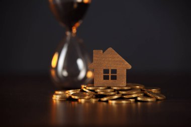Bozuk para ve kum saatinin üzerindeki ev modeli. Yatırım gayrimenkul kavramı