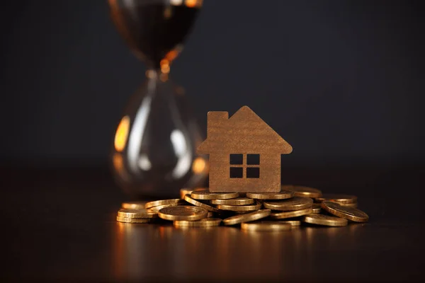 Modell av hus på stapel av mynt och timglas. Begreppet förvaltningsfastighet — Stockfoto