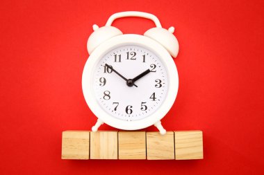 Kırmızı arka planda mesaj ve alarm saati için alanı olan beş tahta küp. Zaman para konseptidir. Süre kısıtlı. İş için son gün. Boşluğu kopyala