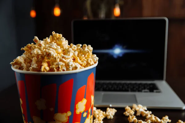 Memiliki malam yang baik menonton film pada laptop dengan popcorn. Makanan cepat saji. Jagung — Stok Foto