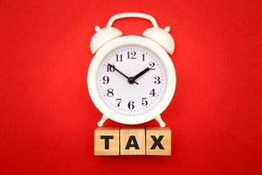 Vergi konseptini ödeme zamanı. Ahşap küpler ve kırmızı arkaplanda alarm saati