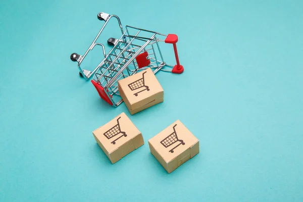 Shopping cart with boxes isolated on blue background. The concept of an online shopping and delivery