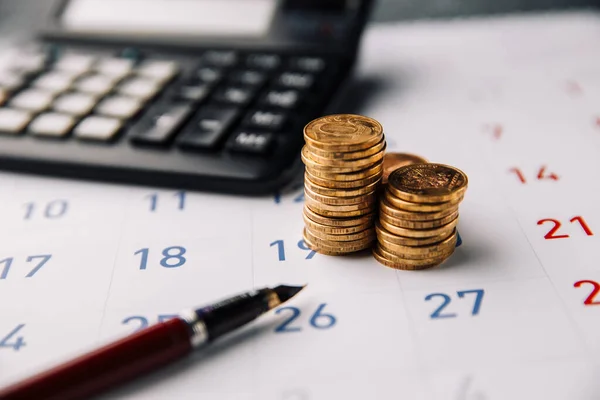 Bir ofiste takvim, hesap makinesi ve bozuk para yığını