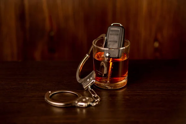 차 열쇠와 수갑이 달린 위스키. 음주운전에 대한 개념 — 스톡 사진