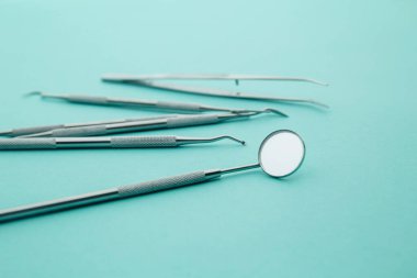 Diş aletleri, ayna, spatula, mavi arka planda cımbız.