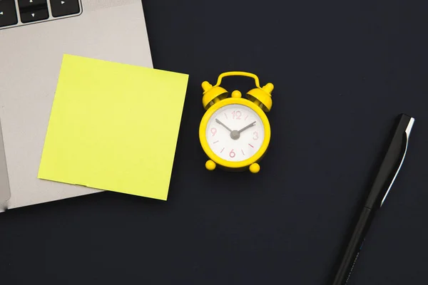 Laptop con adesivo, spazio per testo, allarme giallo e penna su sfondo blu scuro. Vista dall'alto. Business e concetto di lavoro a distanza — Foto Stock