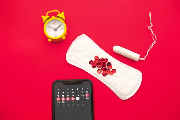 Calendário de menstruação em smartphone com tampão de algodão, almofada sanitária, brilhos vermelhos. Mulher dias críticos, mulher proteção de higiene — Fotografia de Stock