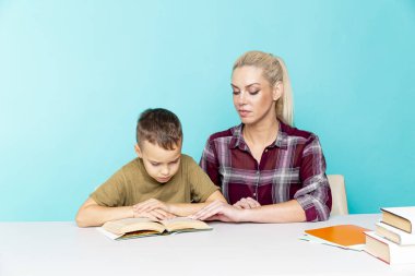 Anne, oğluna pembe arka planda ödevlerinde yardım ediyor. Uzak eğitim