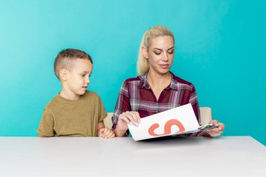 Anne, oğluna pembe arka planda ödevlerinde yardım ediyor. Uzak eğitim