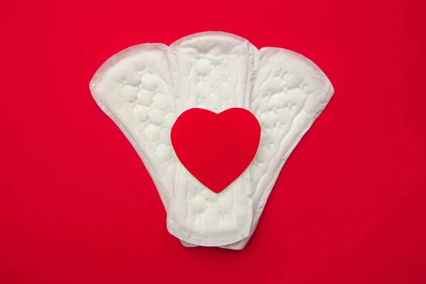 Menstruation period pain protection. Daily pads and red heart on red background