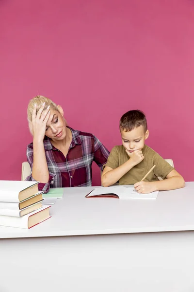 Kleiner Schüler macht Hausaufgaben mit Mutter, Zusammenarbeit in der Familie, Elternschaft — Stockfoto