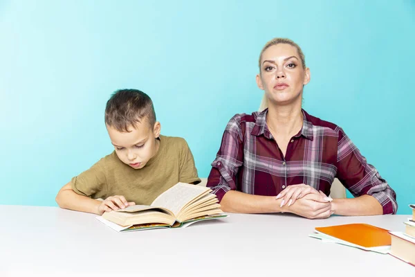 Tarefa de casa à distância com a mãe em casa no momento da quarentena. Menino com a mãe sentada na mesa e estudando . — Fotografia de Stock