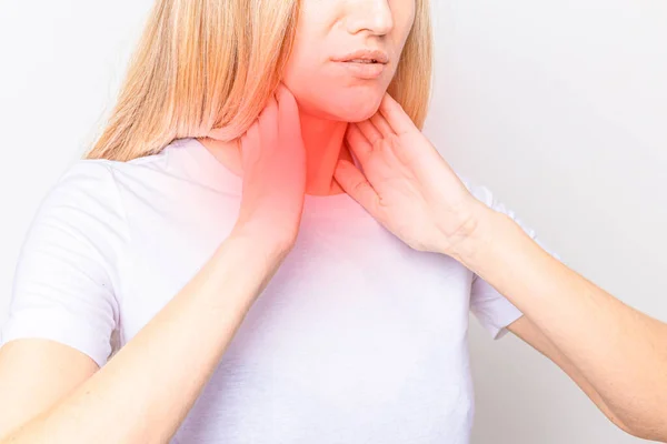 Mujer revisando la glándula tiroides sola. Primer plano de mujer en camiseta blanca tocando cuello con mancha roja. El trastorno tiroideo incluye bocio, hipertiroides, hipotiroides, tumor o cáncer. Asistencia sanitaria. — Foto de Stock