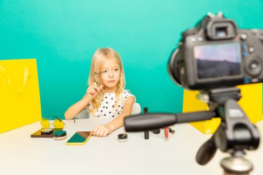 Evde kameranın önünde vlog için konuşan mutlu kız. Küçük çocuk blog yazarı olarak çalışıyor, internet için video dersi kaydediyor..