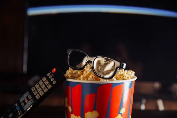 Whatching 3D movie at home with friends concept. Popcorn in the bright bowl, glasses and TV remote control isolated.