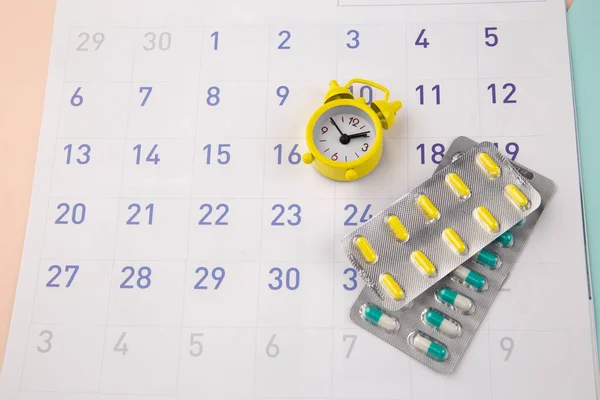 Control Time to take pills. Clock with pills on a monthly calendar