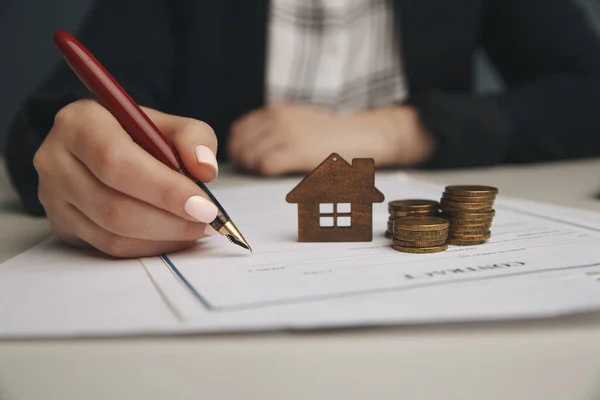 Fechar casa de brinquedo de madeira com mulher assina um contrato de compra ou hipoteca para uma casa, conceito imobiliário . — Fotografia de Stock