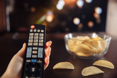 Ev konseptinde televizyon izlemek ve cam kaseden cips yemek.