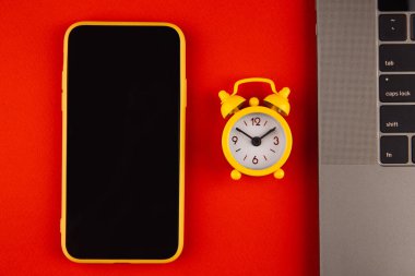 Ev ofisinin çalışma masası konsepti. Kırmızı arkaplanda dizüstü bilgisayar, akıllı telefon ve saat